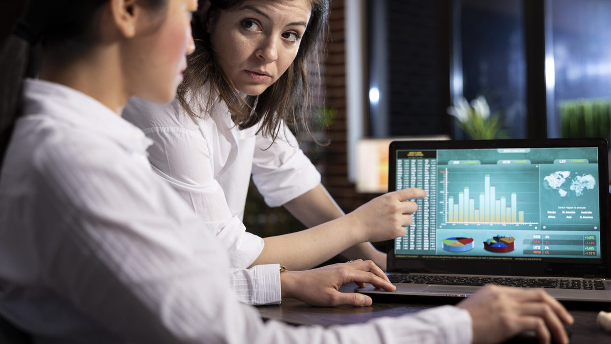 Dos analistas revisan gráficas financieras en una laptop