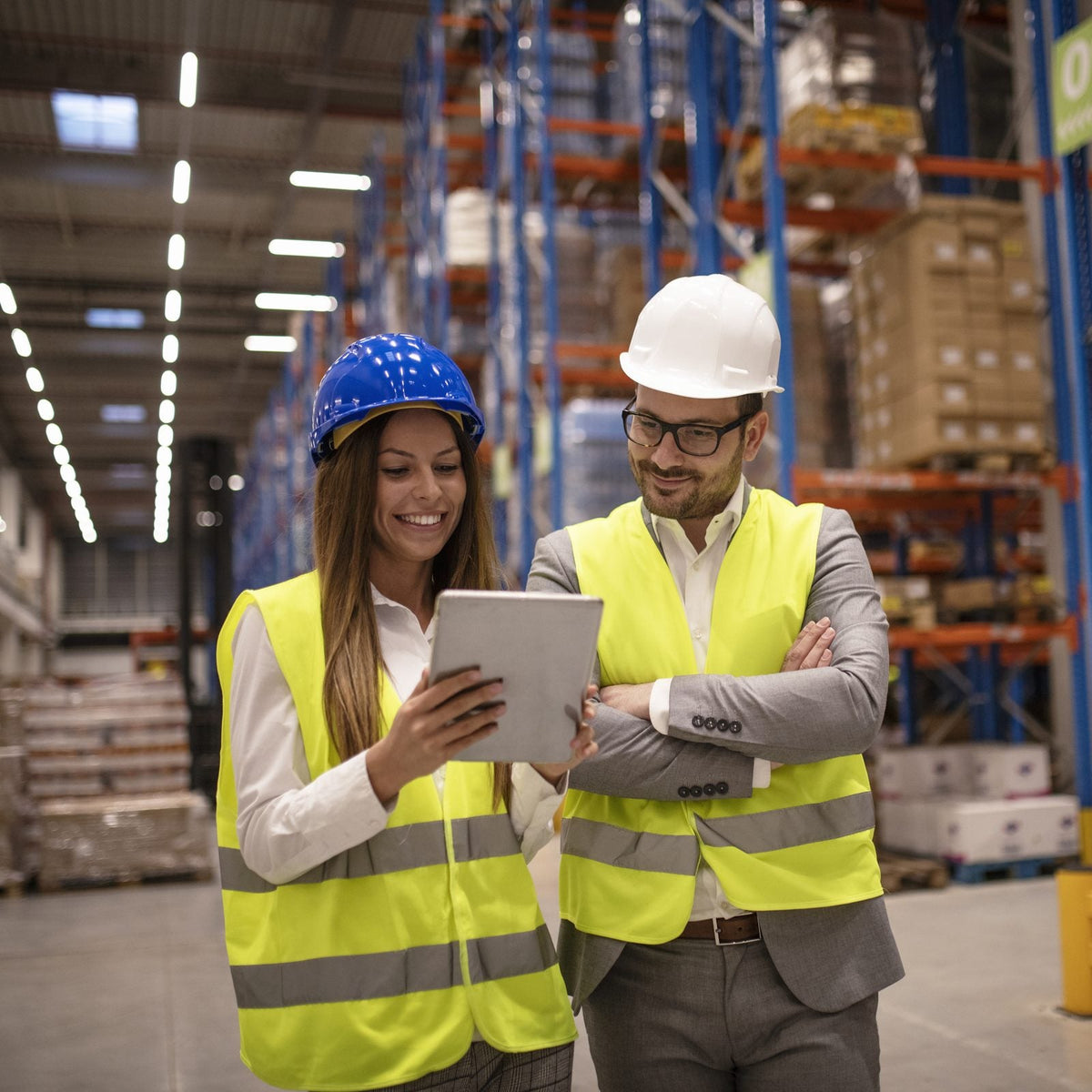 Una gerente y un supervisor revisan el inventario disponible en una tableta dentro de un centro de distribución