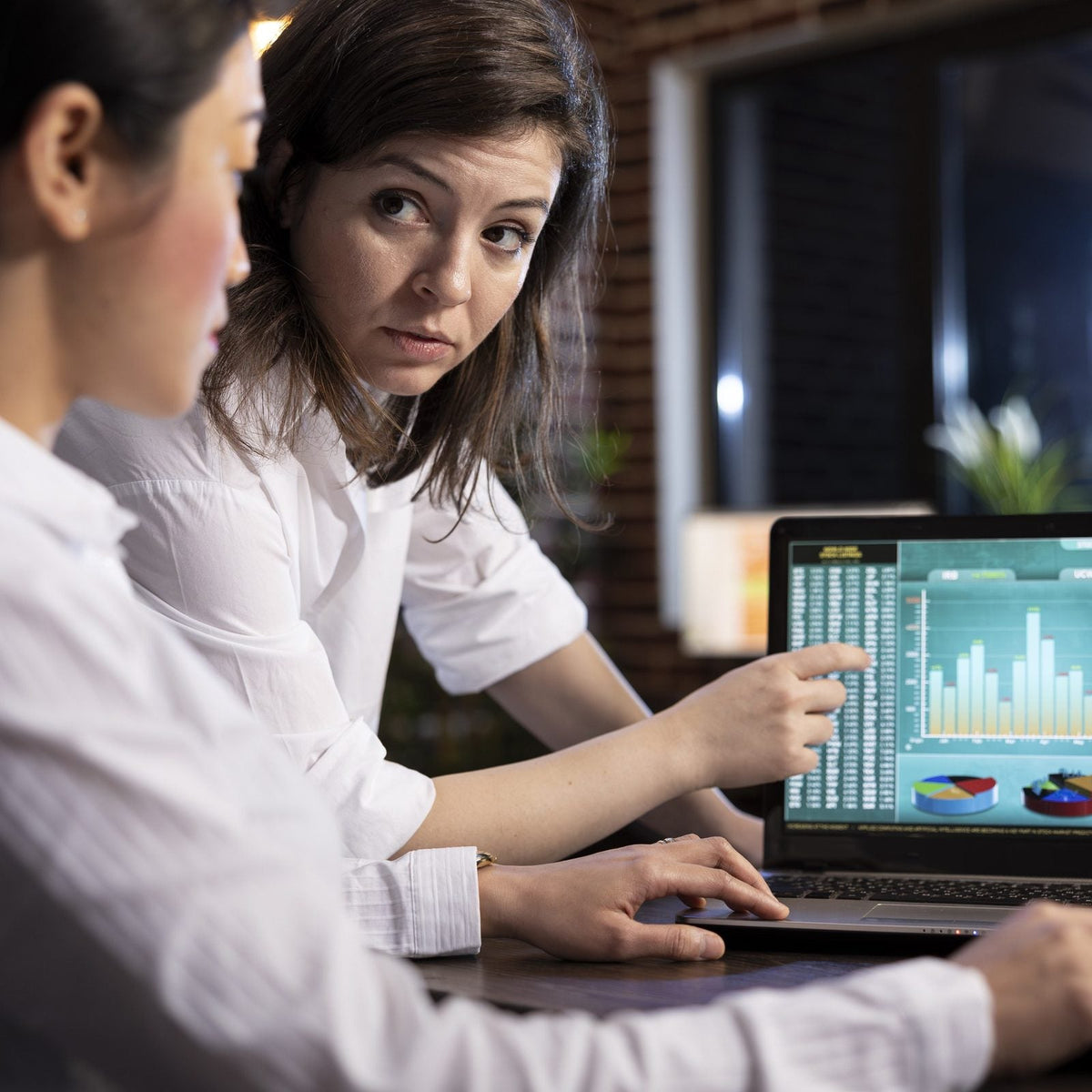 Dos analistas revisan gráficas financieras en una laptop